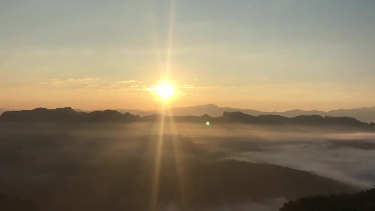 金色的蓬松的云轻轻移动在天空和阳光透过云层与山脉在背景。