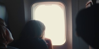 两个快乐的十几岁的乘客孩子，男孩和女孩在飞机上看着窗外的座位上的美景