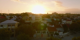 夕阳西下，密集的城镇发展。在住宅区的房子上面飞行。南非伊丽莎白港