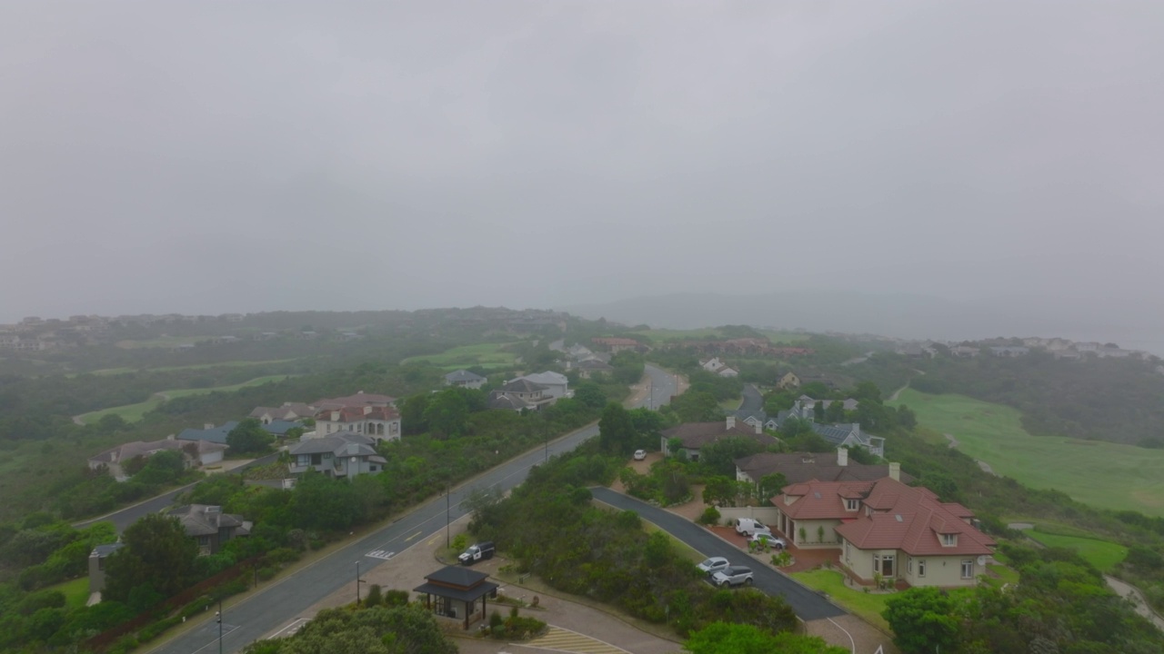 住宅郊区沿路的大型家庭住宅和住宅。向前飞在雾蒙蒙的风景之上。南非伊丽莎白港