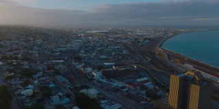 在夕阳照耀下的邮政高层建筑周围飞翔。海湾城市的航拍画面。南非伊丽莎白港