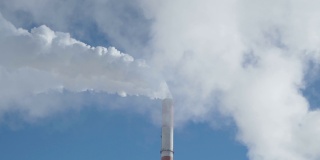 阳光明媚的日子里，工厂里一缕缕的炊烟衬托着蓝天。生态概念，环境污染
