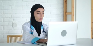 一名戴着头巾的妇女正在接受在线培训，以提高她作为一名医生的资格。穆斯林国家的医学教育。这位未来的医生正在录制一场关于治疗的演讲
