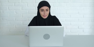 一位穆斯林妇女使用新技术与外界沟通。一名戴着黑色头巾的女性用笔记本电脑通过视频会议与同事交流