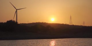 在印度古吉拉特邦的Wankaner，夕阳下的风车剪影。在黄金时段，除了太阳，还能看到风车和电塔。日落时的自然背景