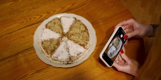 女孩用智能手机的相机拍下了蛋糕。
