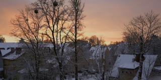 冬天早晨的日出，从屋顶的雪房子雾蒙蒙的景观早期太阳