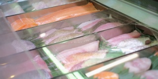 超市橱窗里摆满了各式各样的鲜鱼片，陈列着各种海产海产品。在一家商店出售的红色肉色的鲑鱼片，用于制作寿司和其他鱼类菜肴