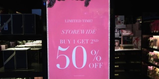 时装店展示的大粉色购物海报，服装和配饰的折扣优惠。50%的折扣吸引了大量的买家来进行有利可图的购买