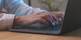 一个男人的手打开笔记本电脑，在键盘和触摸板上打字