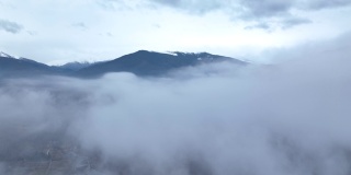 无人机在湖面上空的云层中飞行，露出了那座山。冬天的景色
