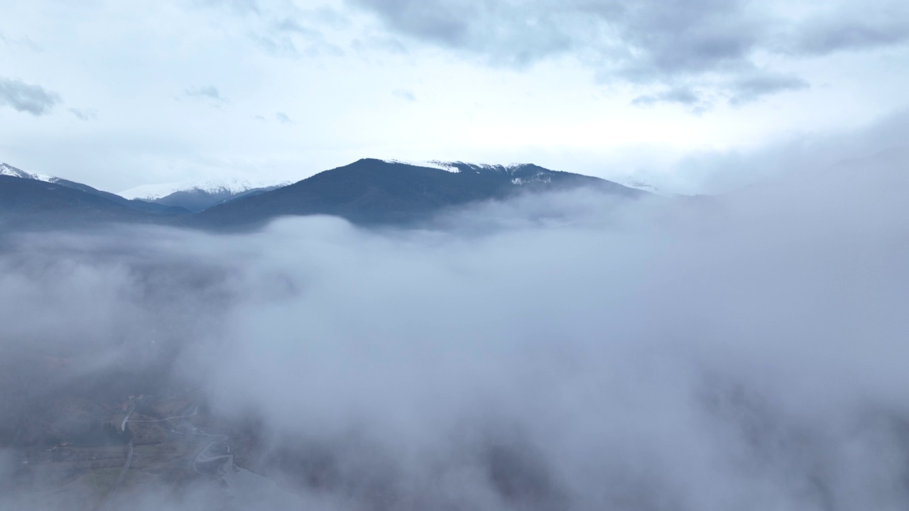无人机在湖面上空的云层中飞行，露出了那座山。冬天的景色