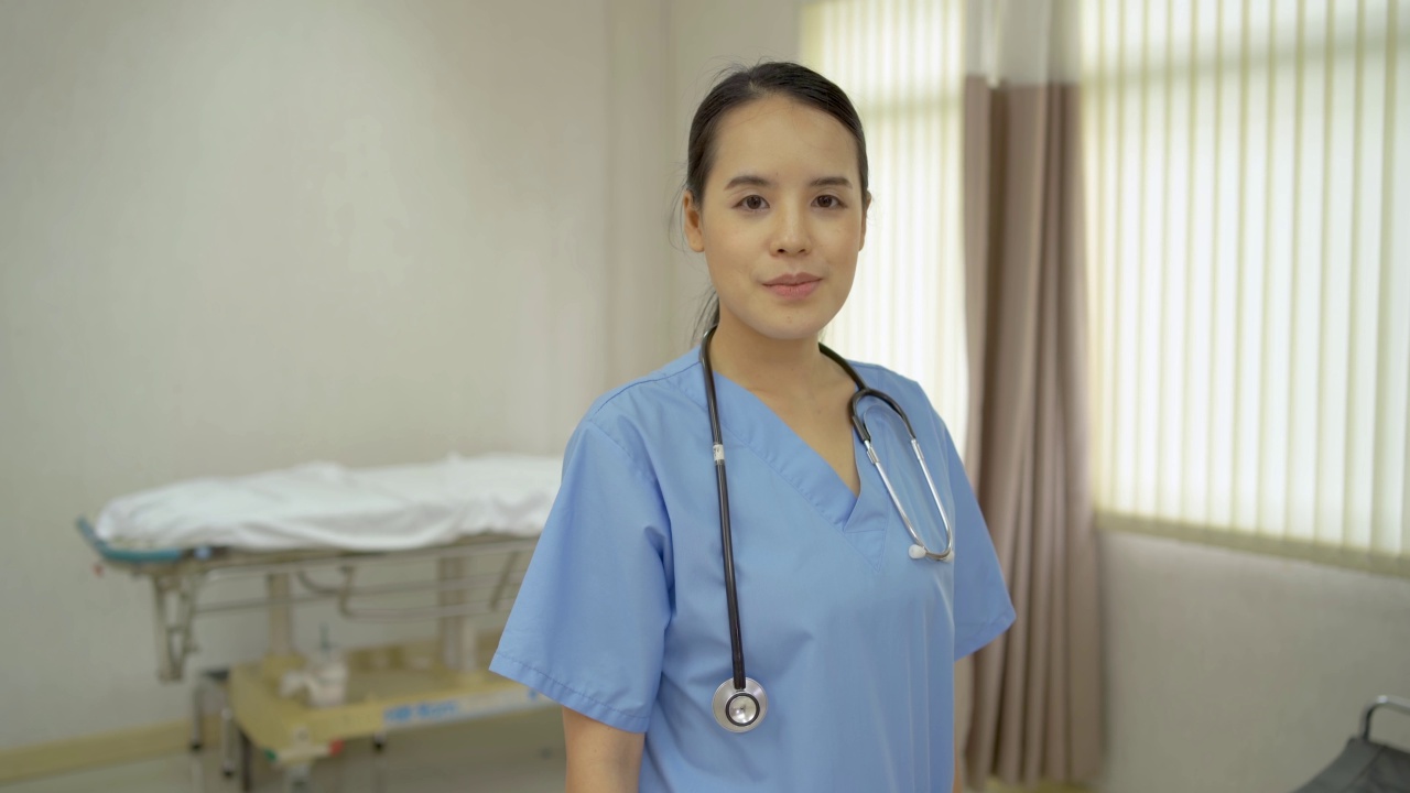近距离肖像开朗年轻美丽的亚洲女性专业医疗护士保健助理站在现代医院和他们的大拇指自信。