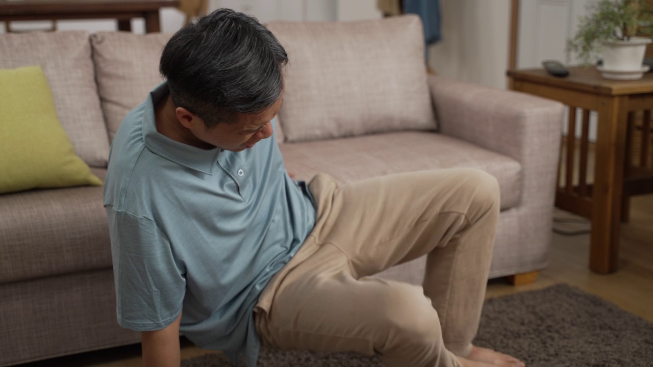 详情图-中国成熟男人坐在沙发上休息时，腰疼，呻吟，非常不舒服。老年人在家跌倒风险观念
