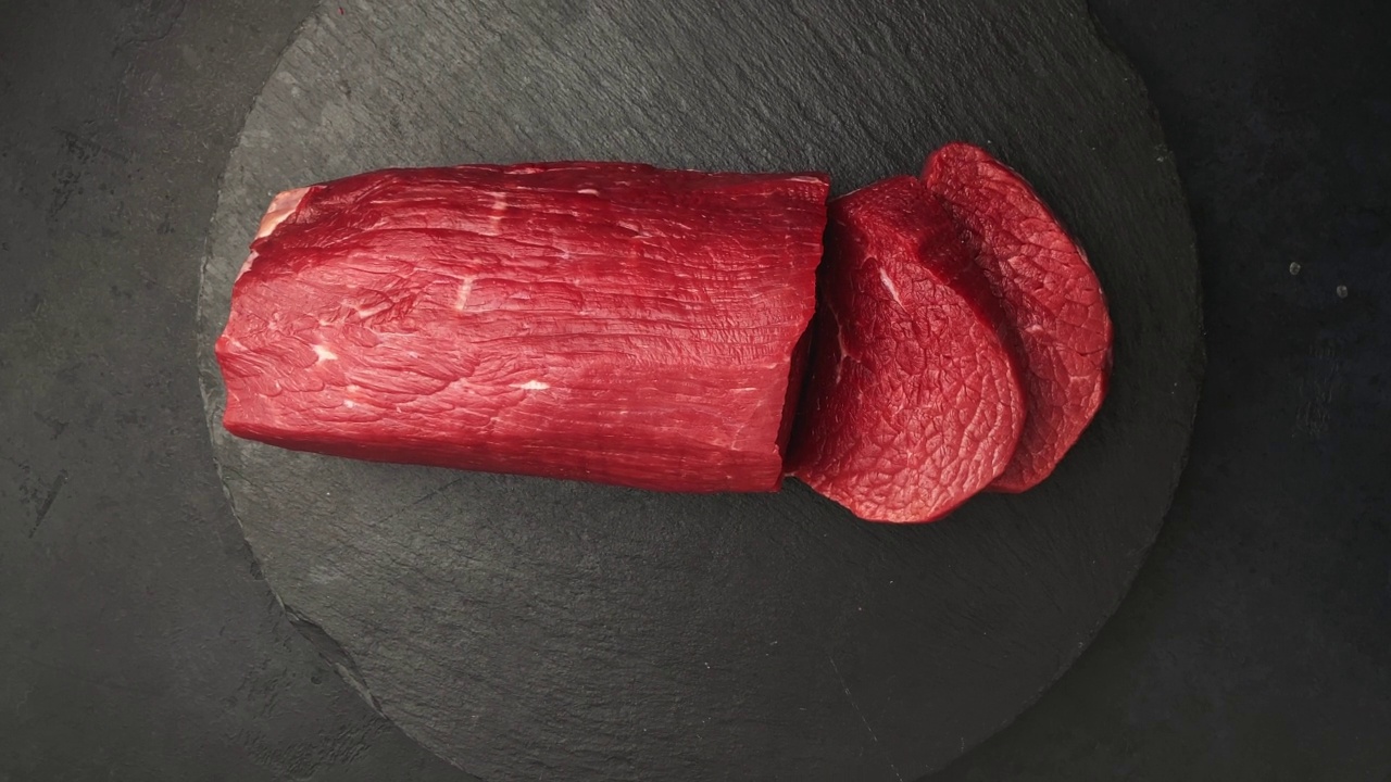新鲜生牛肉上黑底烤牛肉，360度旋转。俯视图