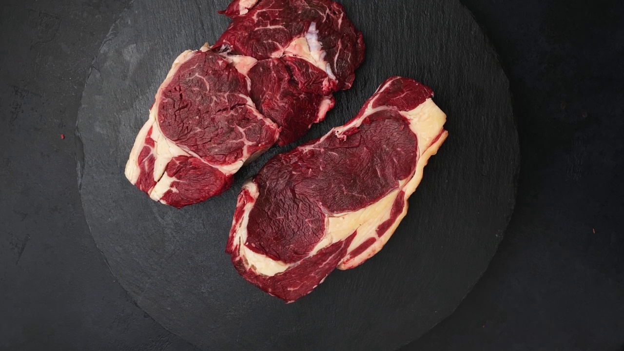 新鲜生牛肉纽约牛排黑底，360度旋转。俯视图