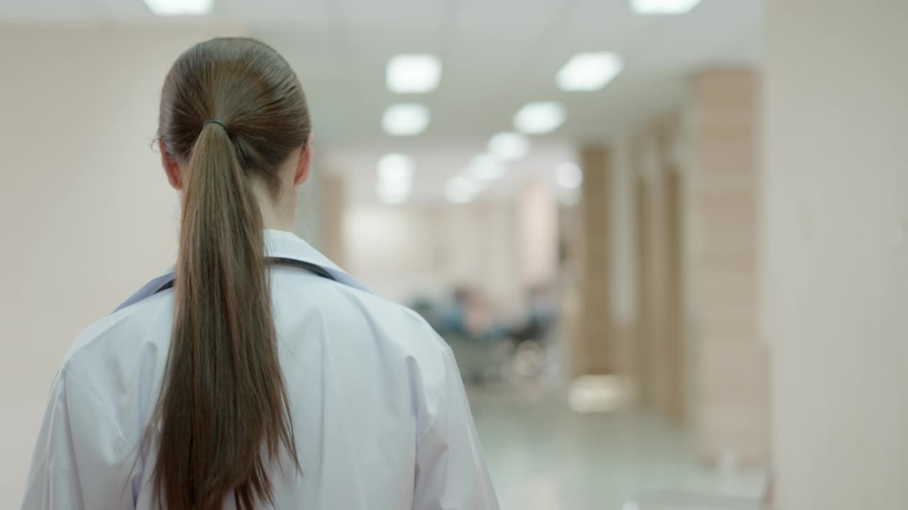 穿着白色医疗服的专业女医生或外科医生具有专业知识。在医院的检查室或手术室里急匆匆地行走治疗病人。