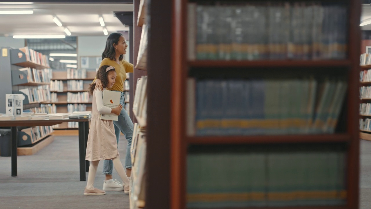 詳情圖-兩個(gè)女人坐在圖書館的地板上一起看書。可愛的女兒和媽媽在圖書館。