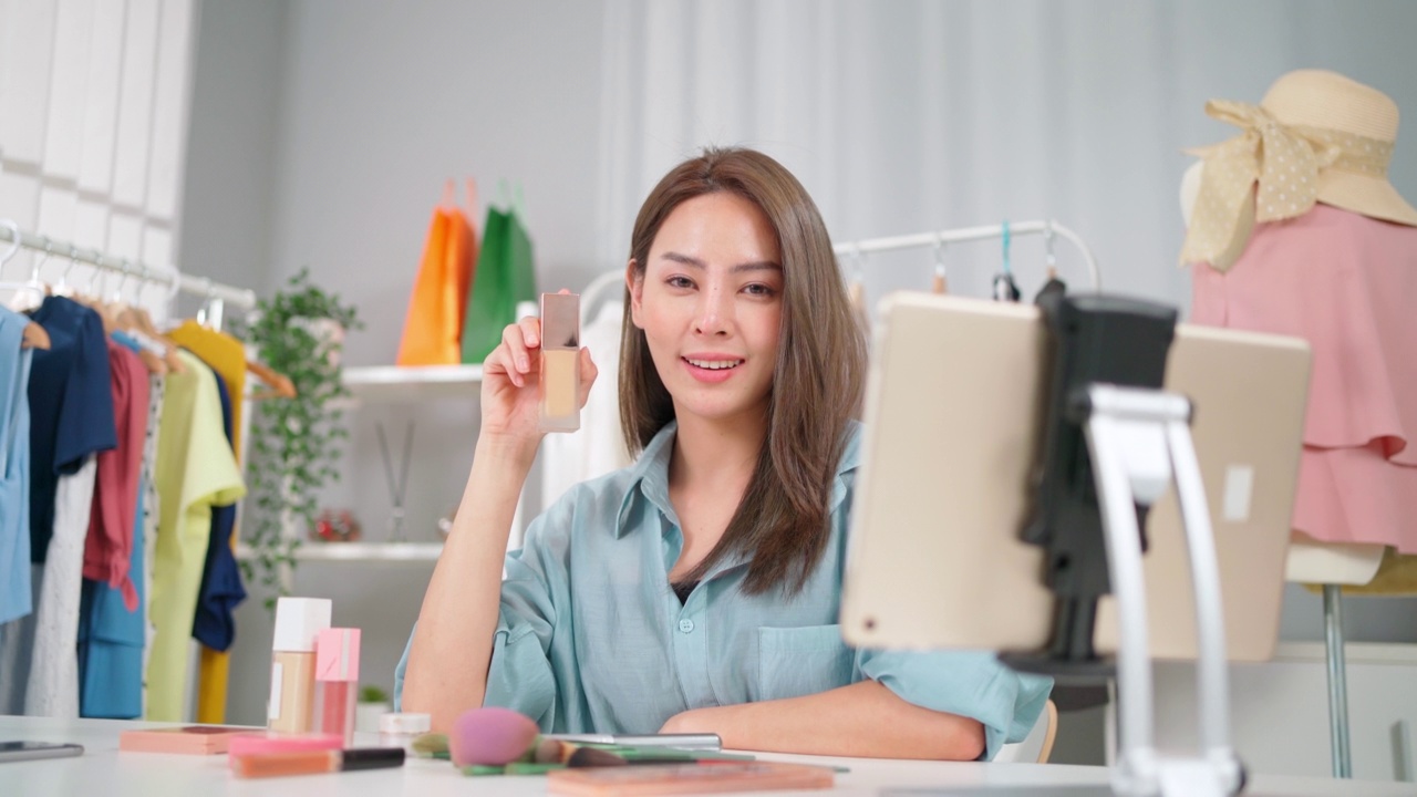 詳情圖-年輕的亞洲女性工作在網(wǎng)上電子商務購物在家里。創(chuàng)業(yè)在線時尚布料業(yè)務。通過使用平板電腦視頻電話設(shè)置直播，向客戶展示產(chǎn)品。買賣概念
