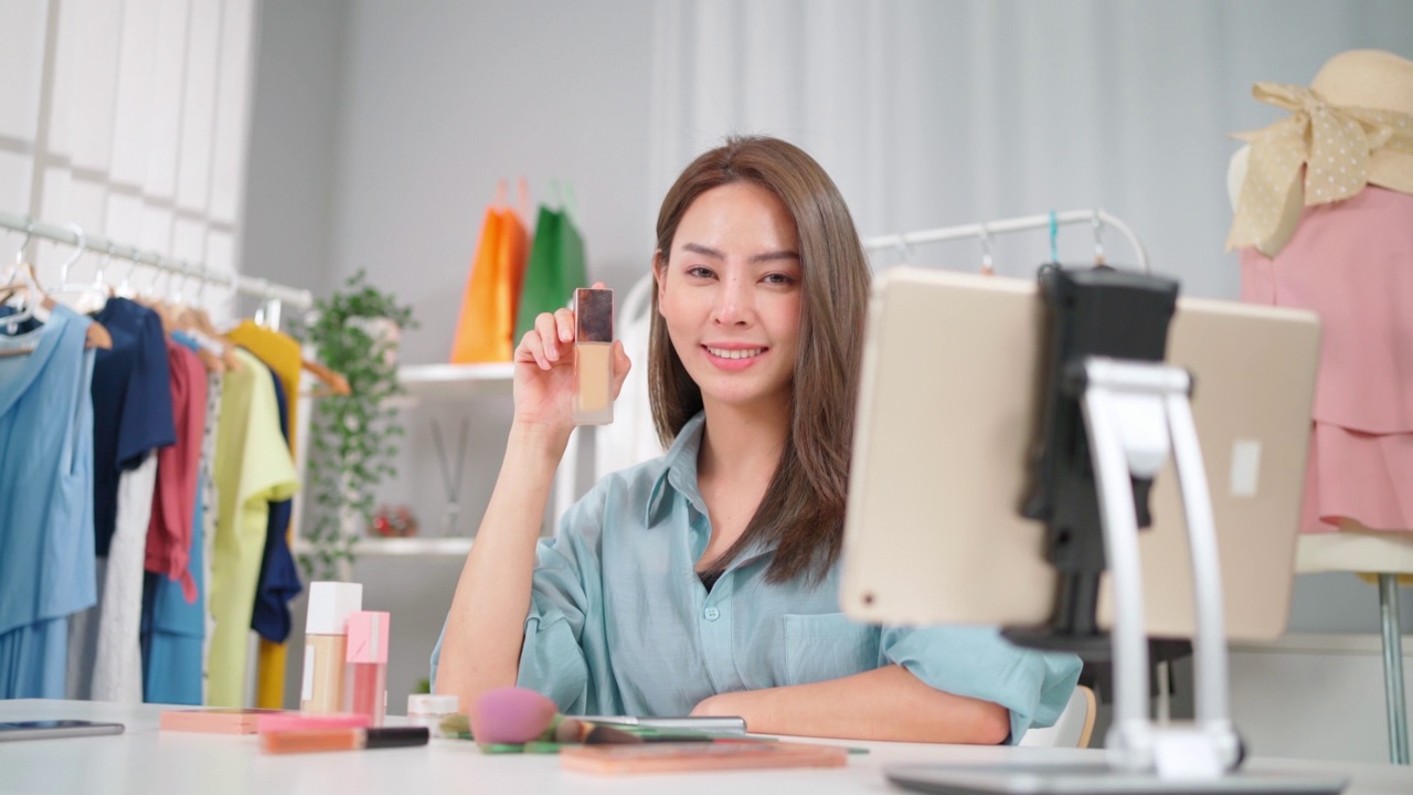 詳情圖-年輕的亞洲女性工作在網(wǎng)上電子商務購物在家里。創(chuàng)業(yè)在線時尚布料業(yè)務。通過使用平板電腦視頻電話設(shè)置直播，向客戶展示產(chǎn)品。買賣概念