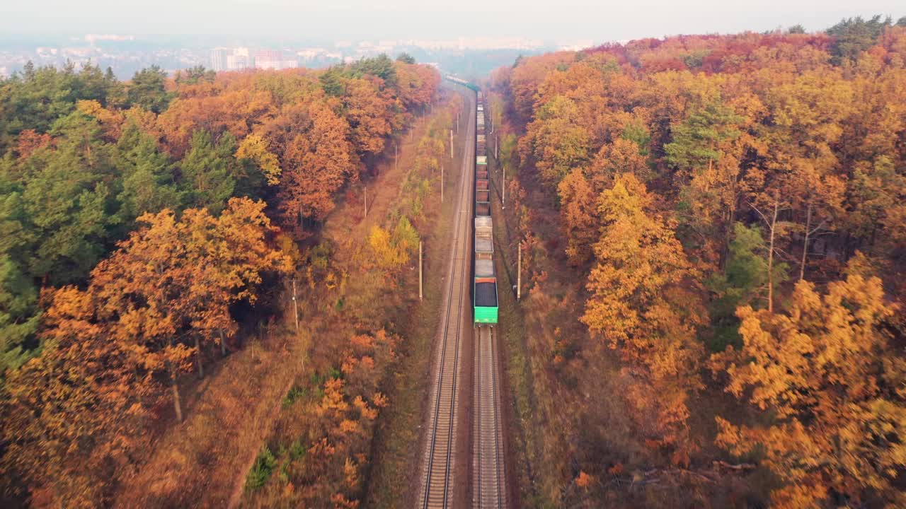 貨運(yùn)列車在美麗的森林在霧在日出在秋天。鳥瞰圖，秋天的貨車和貨物。工業(yè)。俯視鐵路，霧蒙蒙的樹，橘黃色的葉子。火車站