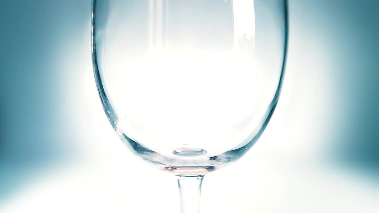 创意宏慢动作4k视频红酒倒入玻璃杯。玻璃杯与倒红酒的特写。用高速电影摄影机拍摄的。