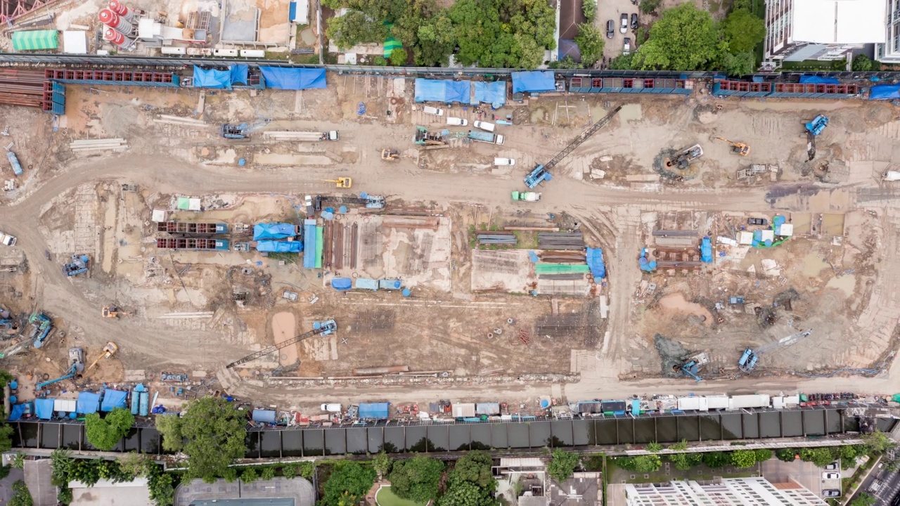 高角度空中自顶向下无人机视角的时间推移在大型建筑施工现场与许多巨大的起重机和机械车辆白天工作。