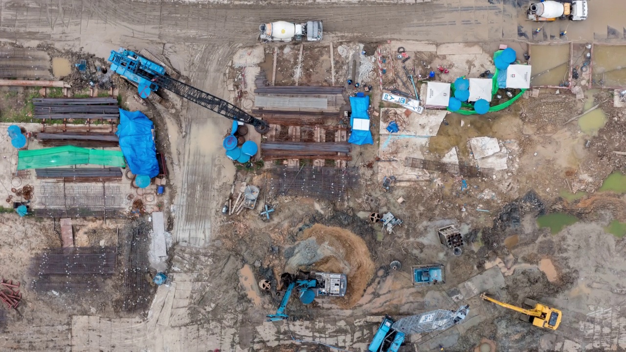 高角度空中自顶向下无人机视角的时间推移在大型建筑施工现场与许多巨大的起重机和机械车辆白天工作。