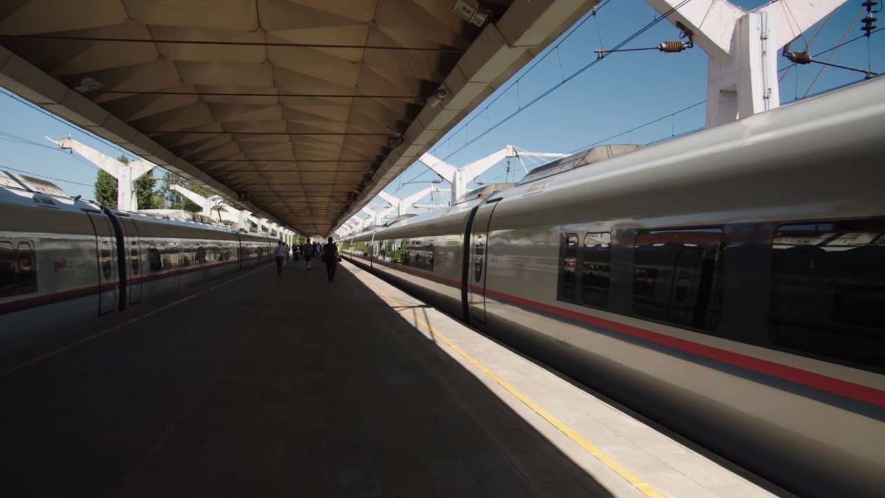 詳情圖-新開的城郊列車在火車站的月臺上行駛，乘客在月臺的天篷下經(jīng)過。長途和郊區(qū)列車的發(fā)車站