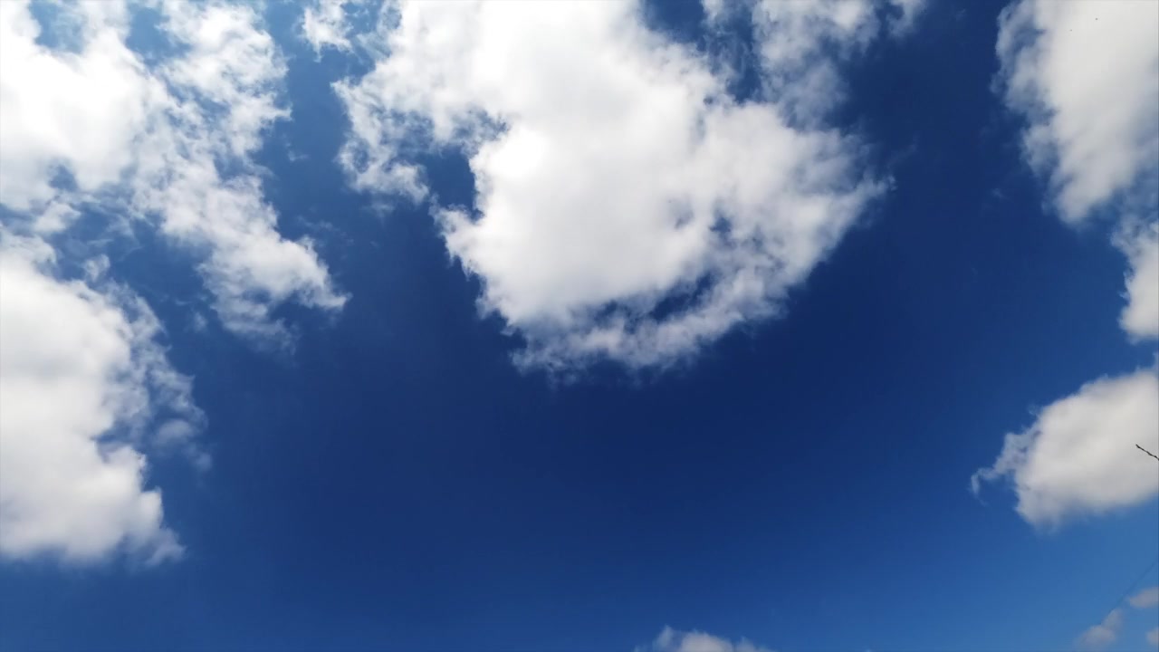 詳情圖-淡淡的白云在明亮的藍(lán)天上迅速地漂浮著。蓬松的云朵反射著夏日陽光的光芒。