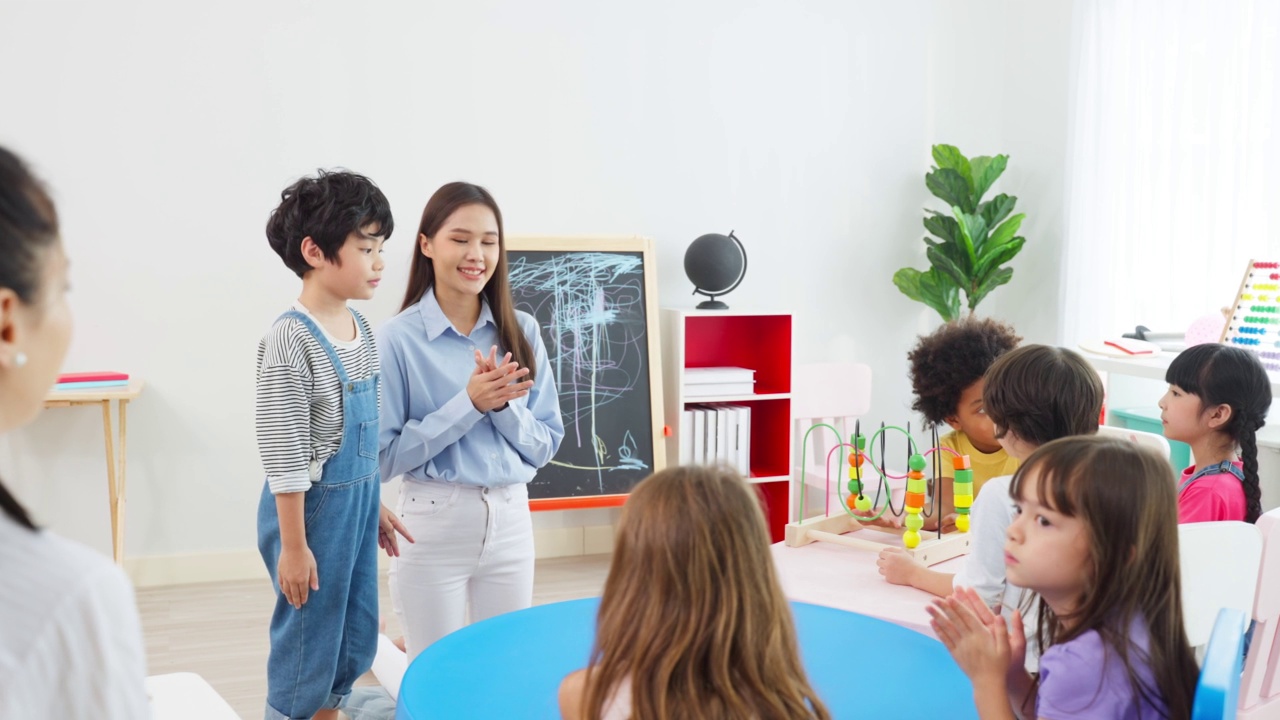 亚洲美丽的年轻女子老师在学校给孩子上课。魅力四射的女教师老师在幼稚园的课堂上用有趣的活动讲解和教育孩子们