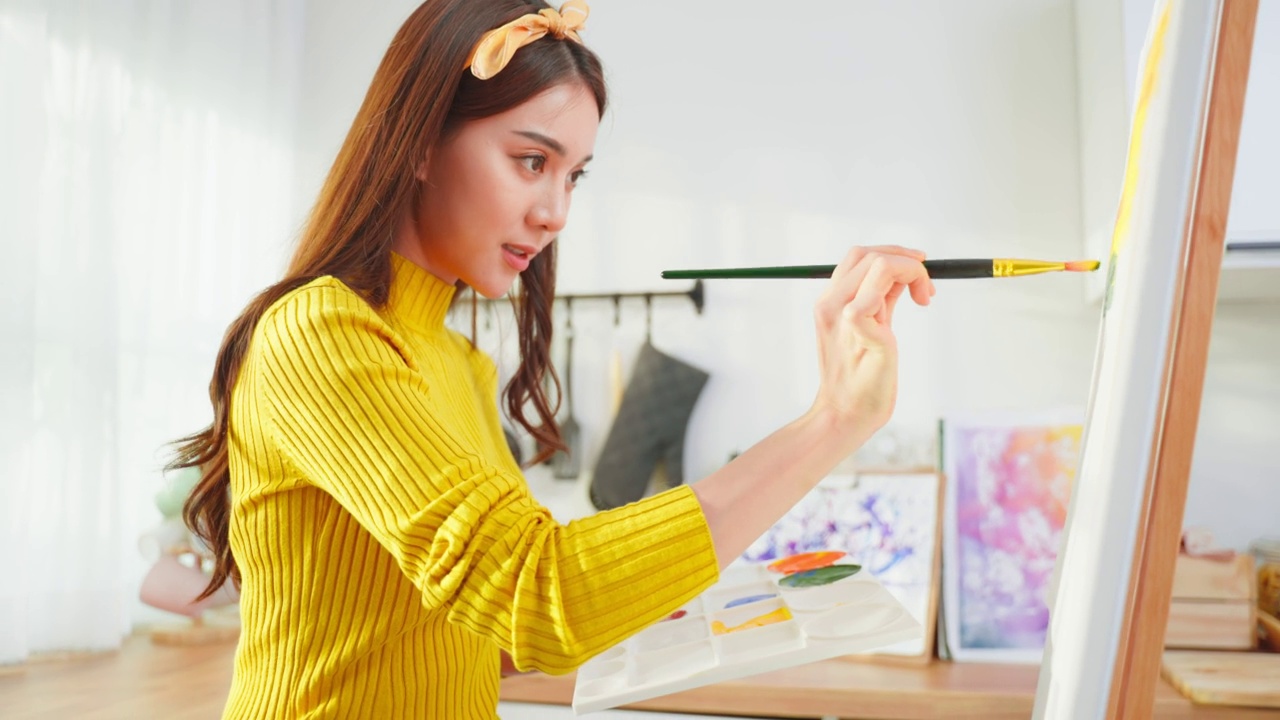 亚洲年轻有才华的女艺术家在家里的画板上着色。有魅力的美女画画，用水彩画和画笔创作艺术品，在家享受创意活动。