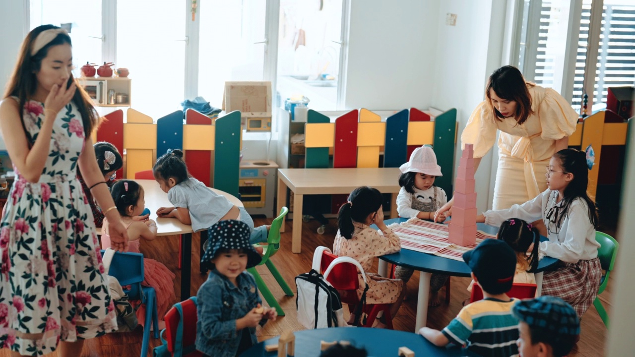 亚洲华人蒙特梭利幼教老师展示学生在教室里用玩具积木搭塔