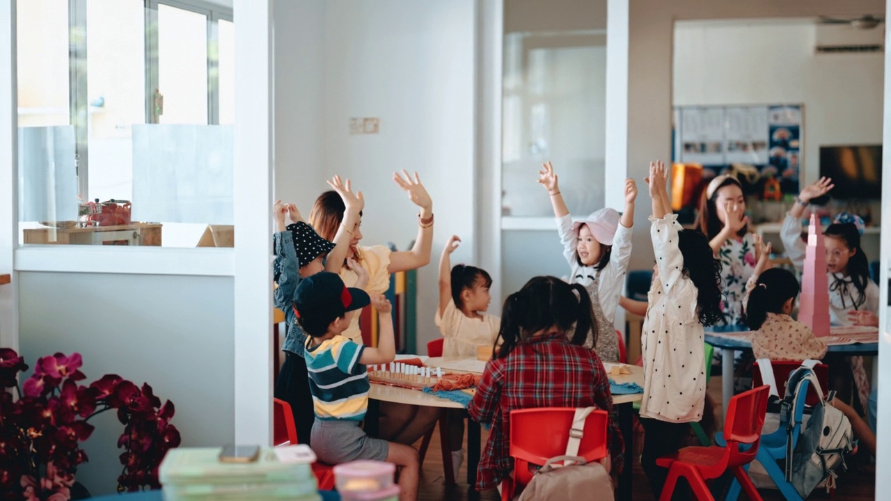 亚洲蒙特梭利学龄前学生在课堂上举手回答问题