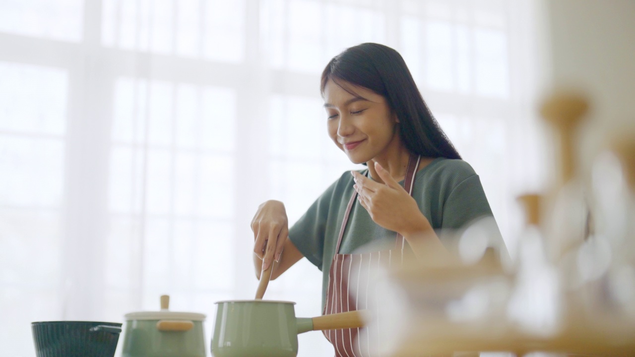 年轻美丽的亚洲女人在家里厨房做饭