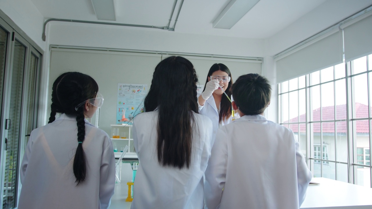 科学家老师在学校实验课上对小学生讲话。