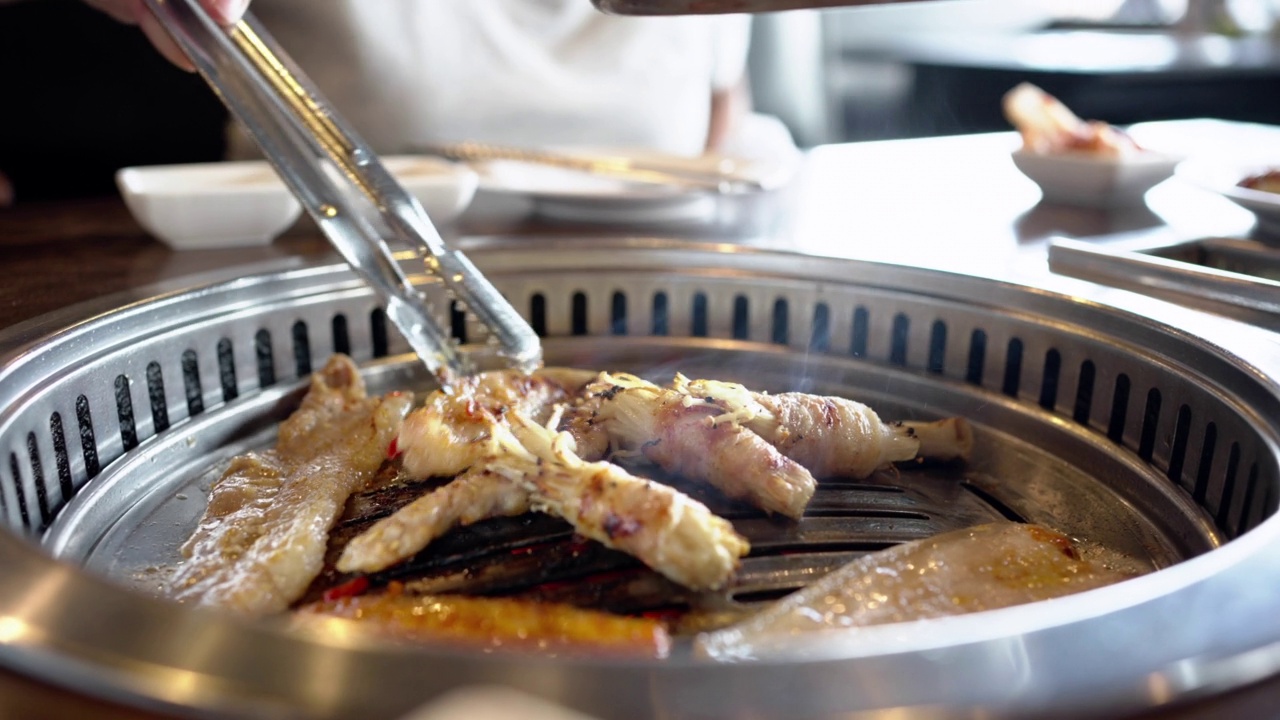 特写一个女人的手烤猪肉烧烤。韩国食物