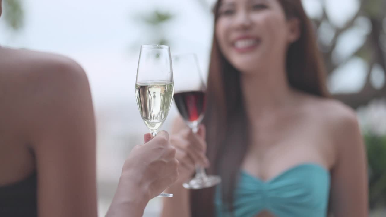 比基尼美女手持香槟杯，碰杯庆祝加入泳池派对。穿着泳装的女人在豪华度假村或酒店的夏季派对的泳池边玩得很开心，享受活动。生活方式，旅行在旅行。