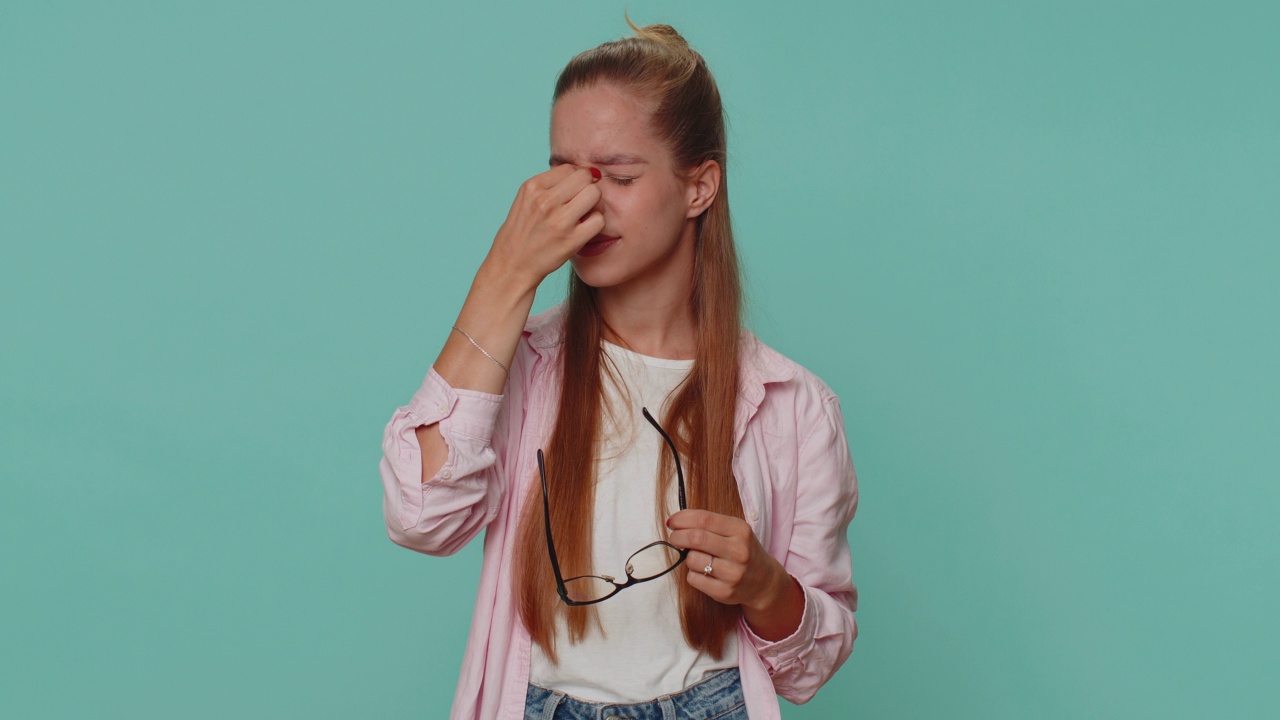 疲惫的少女摘下眼镜，感到眼睛疼痛，因为长时间的工作而过度疲劳