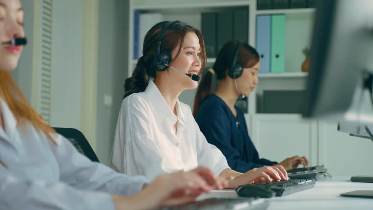 詳情圖-群美麗的商務(wù)女性呼叫中心工作在辦公室企業(yè)。漂亮的年輕員工坐在桌子上，戴著耳機(jī)，使用筆記本電腦在工作場(chǎng)所支持客戶