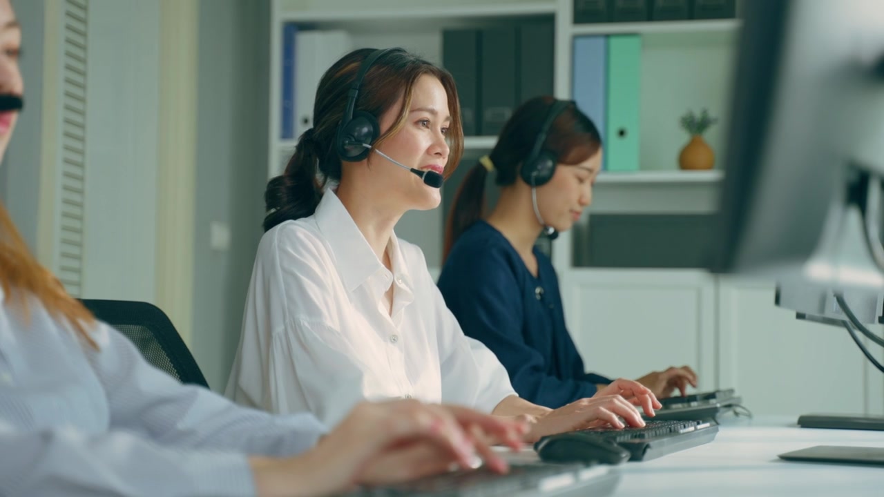 詳情圖-群美麗的商務(wù)女性呼叫中心工作在辦公室企業(yè)。漂亮的年輕員工坐在桌子上，戴著耳機(jī)，使用筆記本電腦在工作場(chǎng)所支持客戶