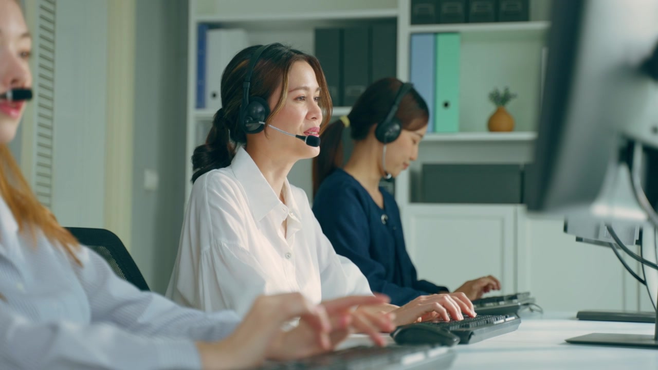 詳情圖-群美麗的商務(wù)女性呼叫中心工作在辦公室企業(yè)。漂亮的年輕員工坐在桌子上，戴著耳機(jī)，使用筆記本電腦在工作場(chǎng)所支持客戶