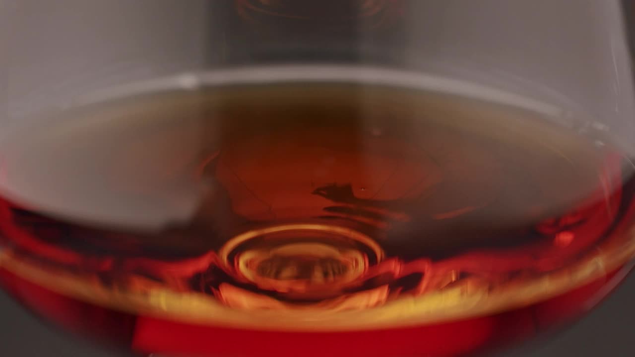 豪华白兰地。玻璃与金色干邑在孤立的黑色背景与烟。