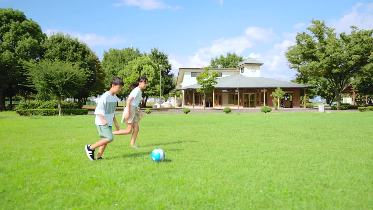 一個(gè)亞洲小孩在藍(lán)天公園里踢足球