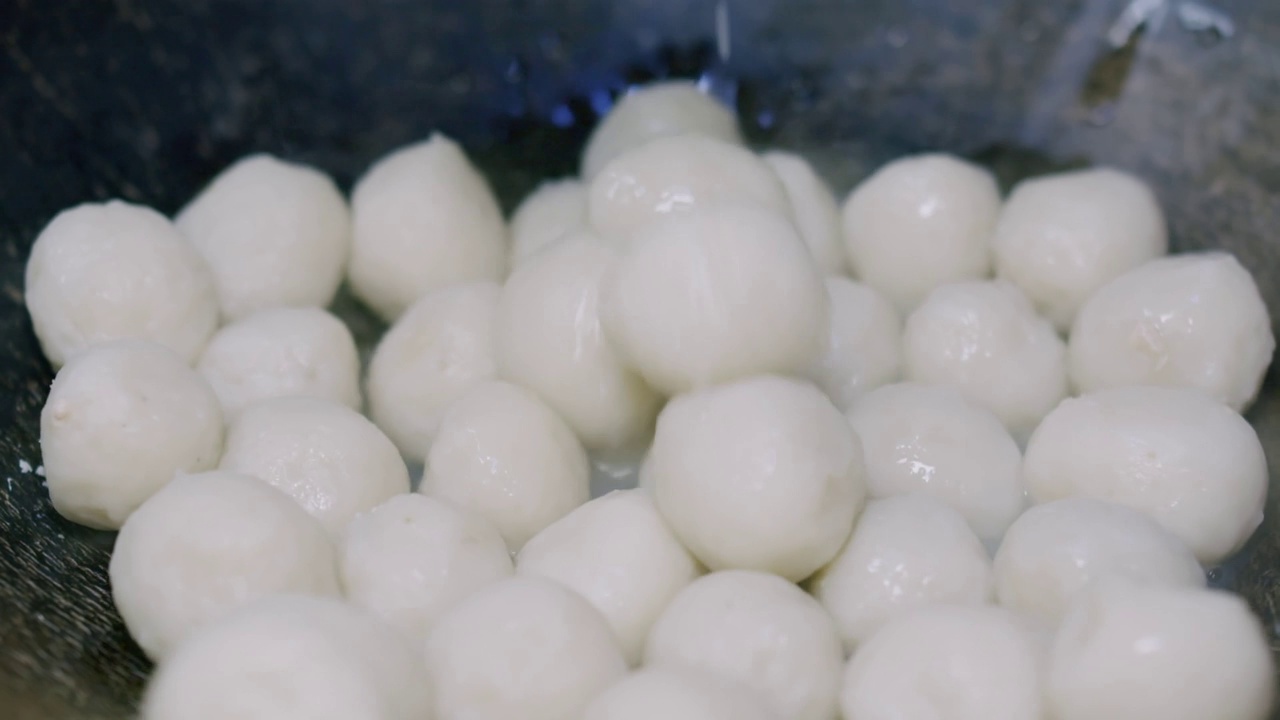 慢动作特写新鲜自制热煮蒸白鱼丸落下和反弹的背景在厨房，传统的亚洲泰国肉丸