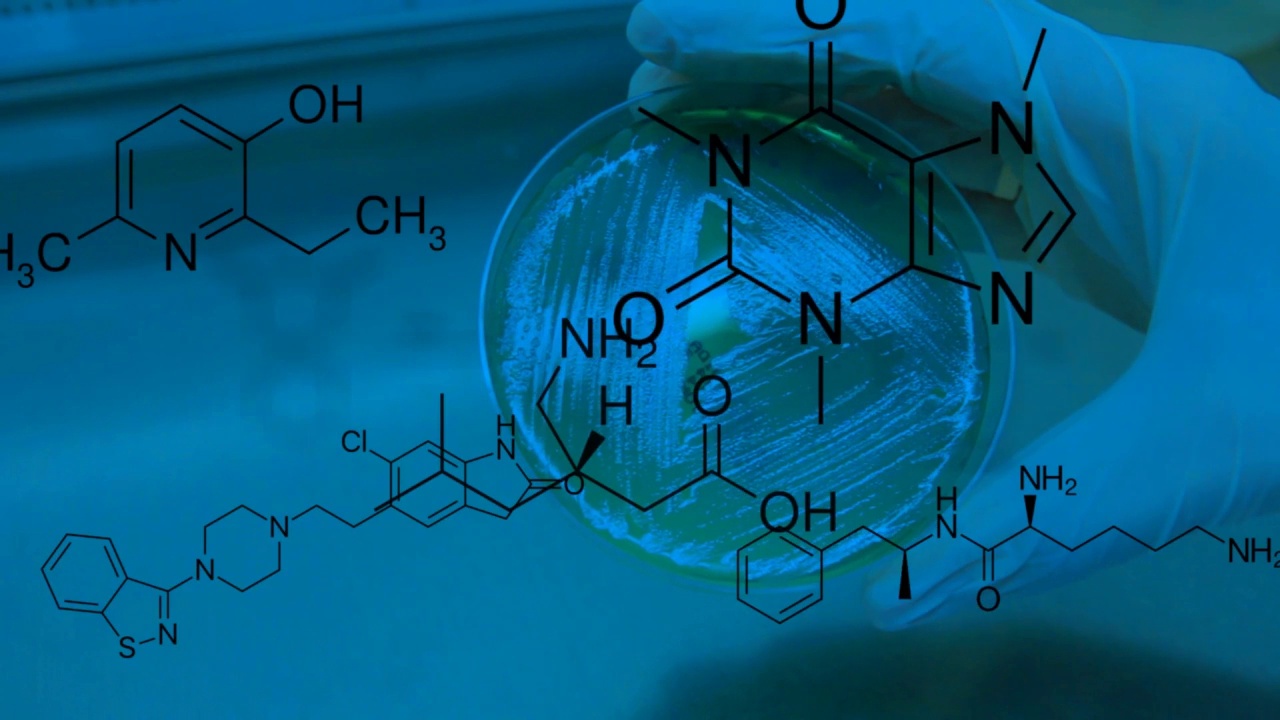 一名研究人员拿着微生物样品，药品、维生素和其他化合物的化学结构出现在覆盖层中