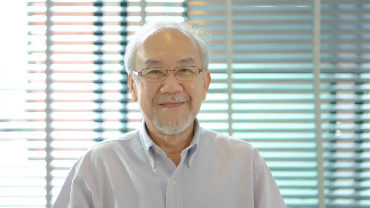 年长的白发老人看着相机，面对有吸引力的老人快乐的微笑，为近距离视频肖像独自在家或养老院，老年人保健