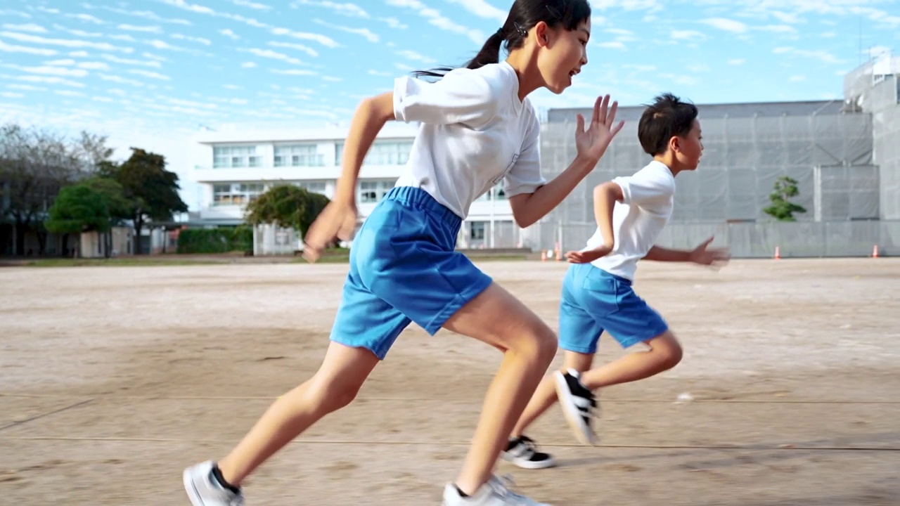 小学的男孩和女孩在学校操场上跑步