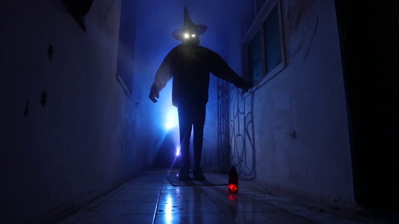 万圣节的概念。黑暗走廊里南瓜头的恐怖剪影。调光与背景上的雾。有选择性的重点。长快门拍摄