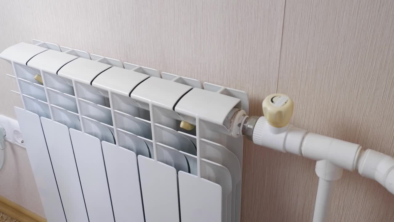 一名女性在家里的房間里用電池和加熱器取暖。手指，手掌保持暖氣片的溫度，靠近。室溫較低。冬季取暖期、季節(jié)。
